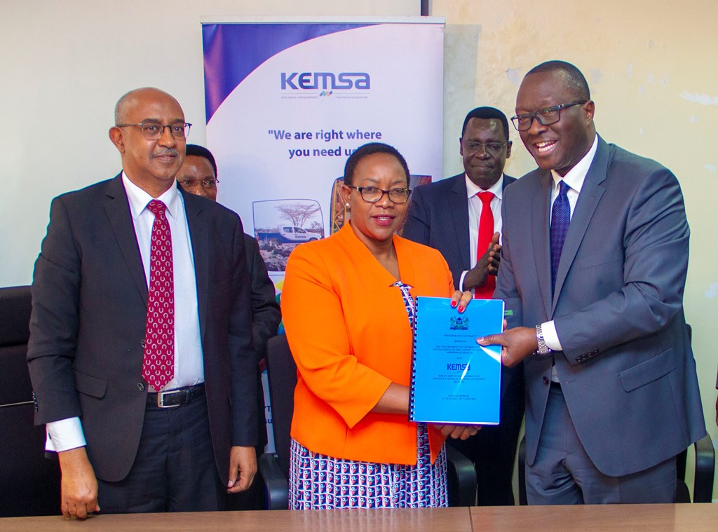 Health CS Sicily Kariuki and Acting Board Chairman Mr.Andrew Onyach display the signed PC. Looking on is a senior MoH official.